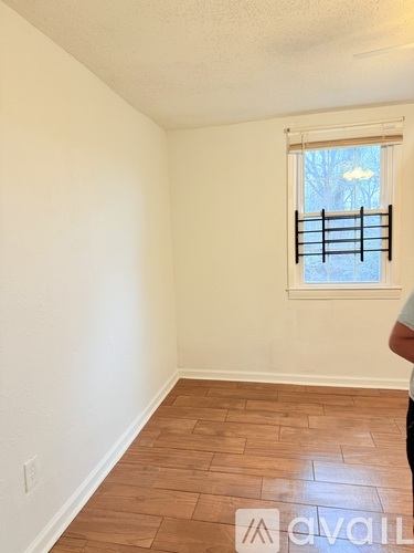 A room with wooden flooring and a window with blinds.