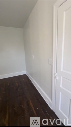 A room with a white door and wooden floor.