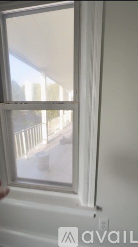A window with a view of a balcony and trees outside.