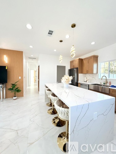A modern kitchen with a white marble countertop and gold accents.