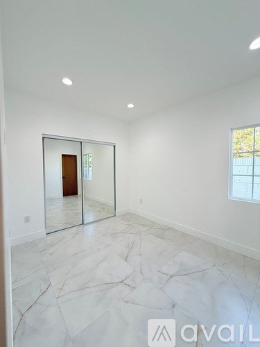 A spacious room with marble flooring and a large mirror on the wall.