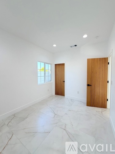 A spacious room with marble flooring and two wooden doors.