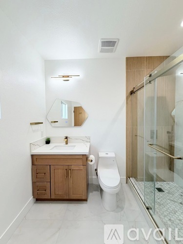 A bathroom with a sink, toilet, and mirror.