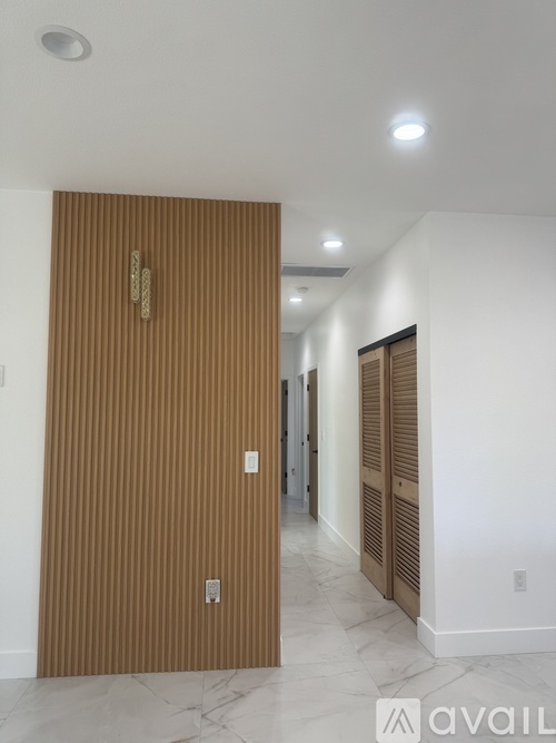 A hallway with a brown door and a marble floor.
