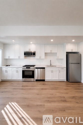 A modern kitchen with white cabinets and stainless steel appliances.