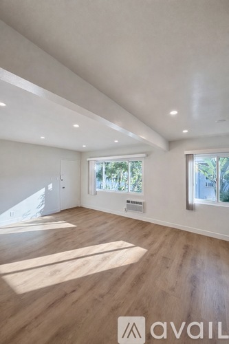 A spacious room with wooden flooring and white walls.