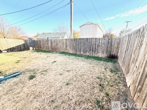 A backyard with a wooden fence and a grassy area.