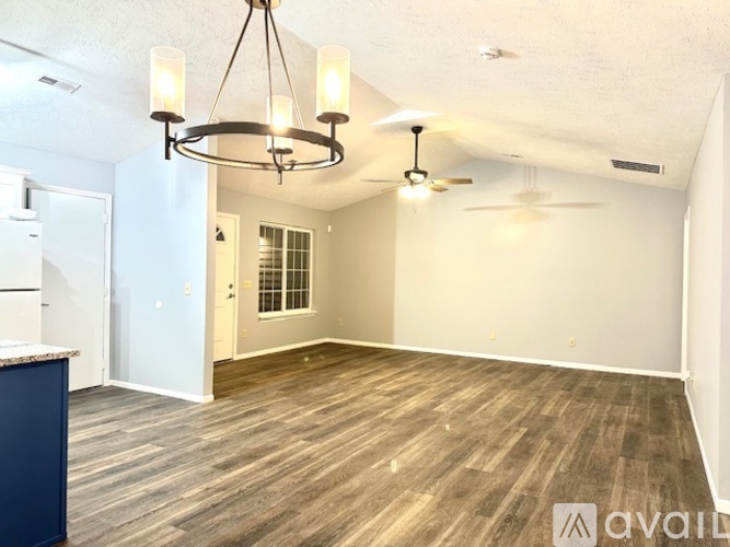 A room with a wooden floor and a chandelier hanging from the ceiling.