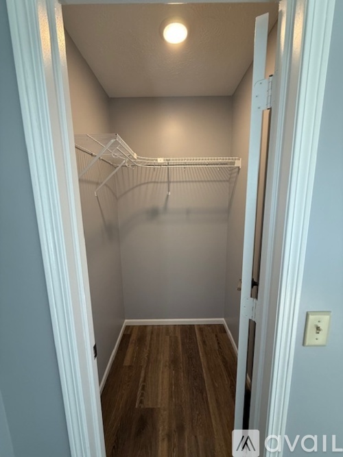 A small, empty room with a wooden floor and a white door.