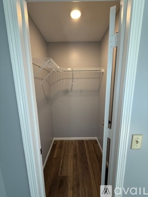 A small, empty room with a wooden floor and a white door.