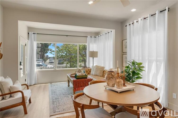 A living room with a wooden table and chairs, a rug, and a potted plant.