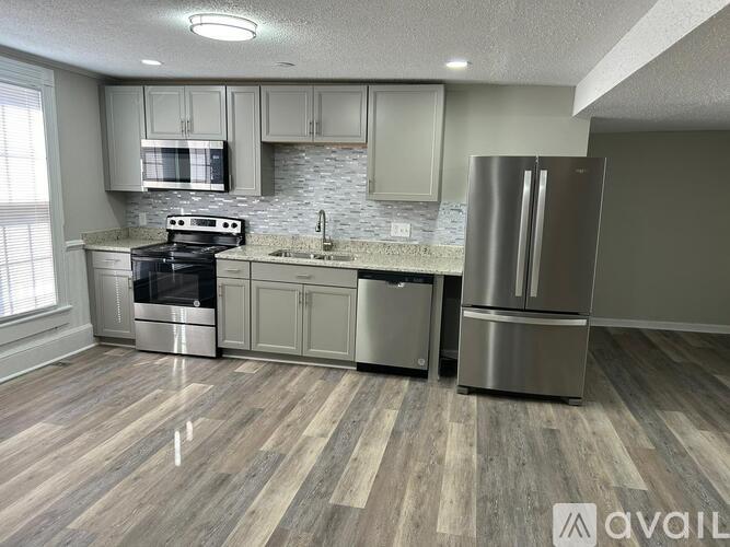 A kitchen with a stove, sink, and refrigerator.