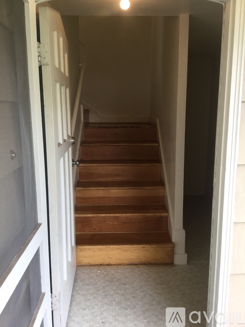 A staircase with a white door on the left and a white wall on the right.
