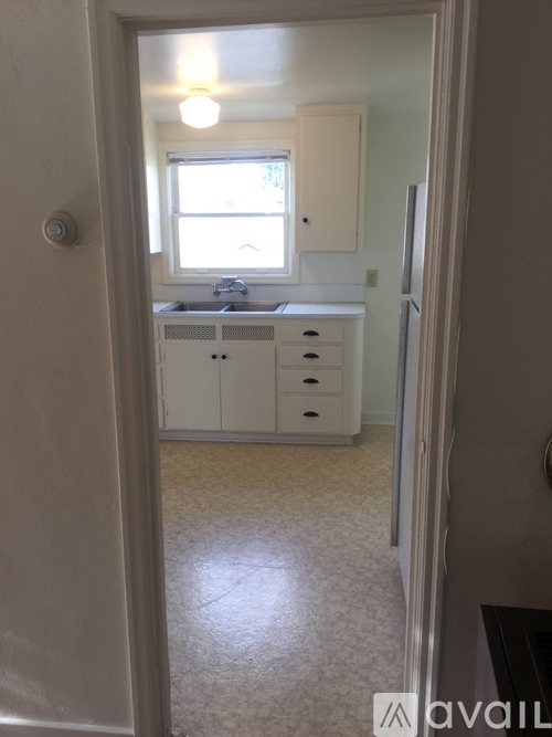 A small kitchen with white cabinets and a window.