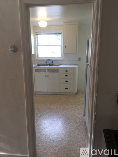 A small kitchen with white cabinets and a window.