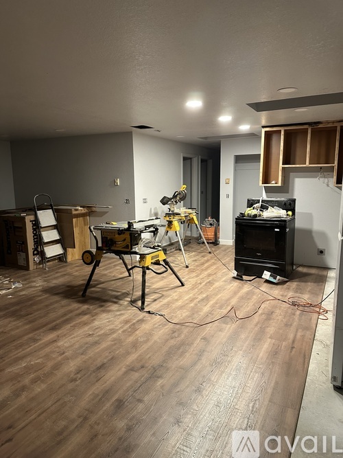 A room with wooden flooring and a workbench with tools on it.