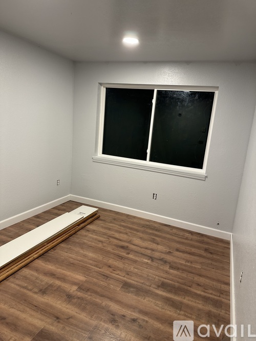 A room with a window and wooden flooring.