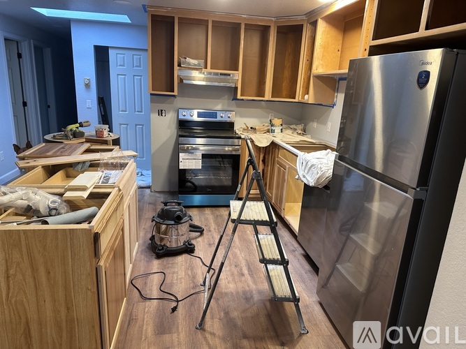 A kitchen with wooden cabinets and a stainless steel refrigerator.