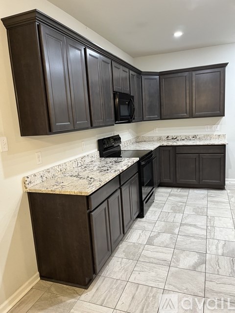 A kitchen with dark brown cabinets and a marble countertop.
