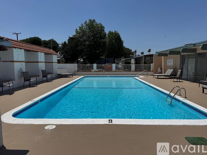 A large outdoor swimming pool surrounded by lounge chairs and trees.