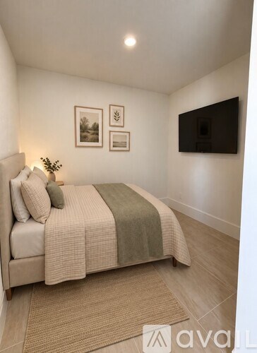 A bedroom with a bed, a plant, and pictures on the wall.
