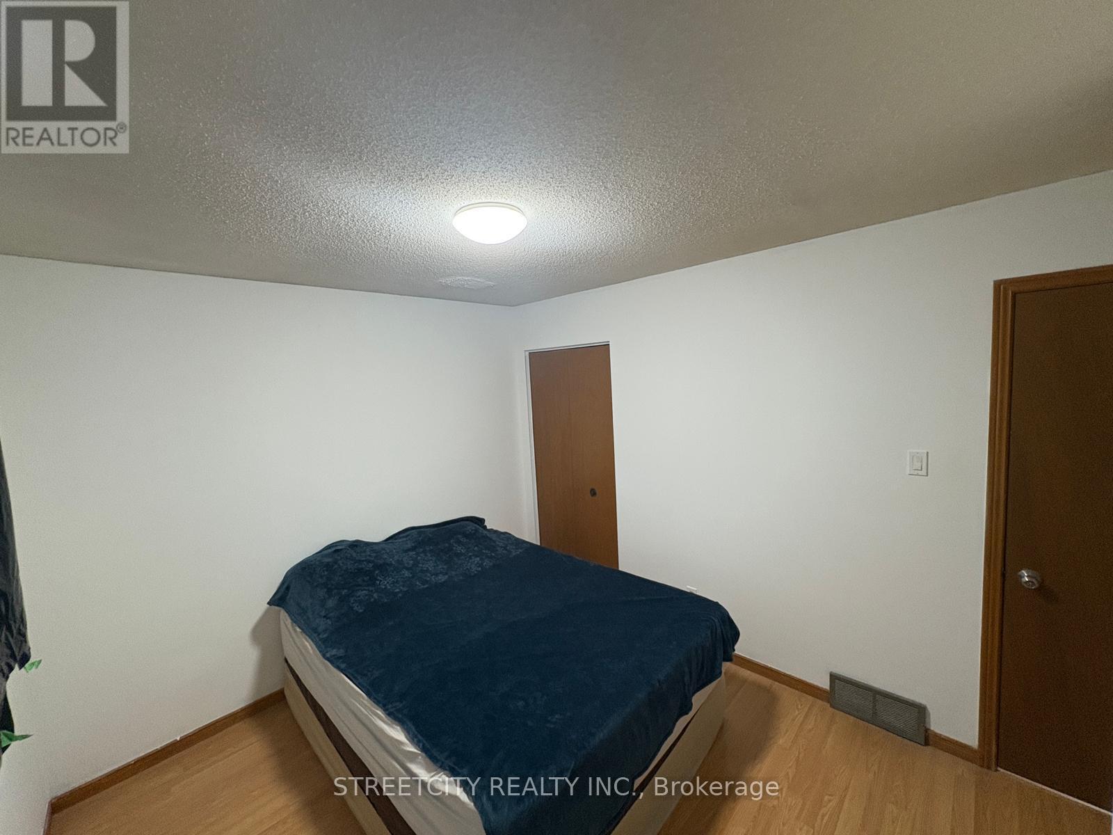 A bedroom with a bed, wooden door, and a white wall.