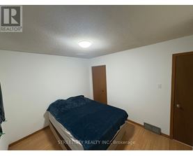A bedroom with a bed, wooden door, and a white wall.