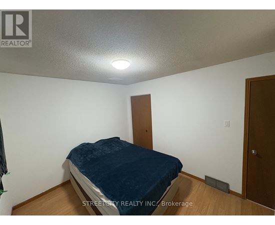 A bedroom with a bed, wooden door, and a white wall.