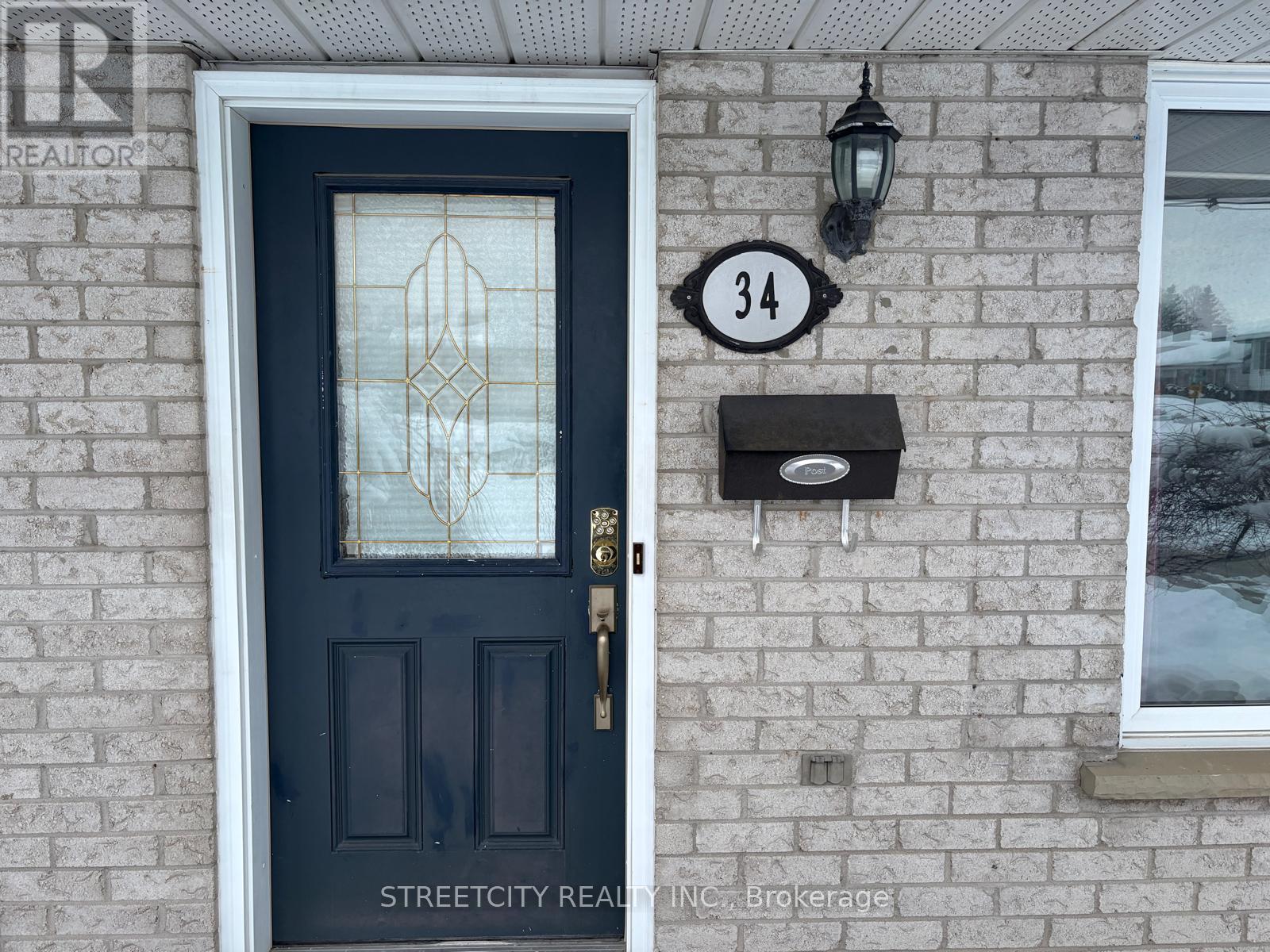 A black door with a glass window and a mailbox on a brick wall.