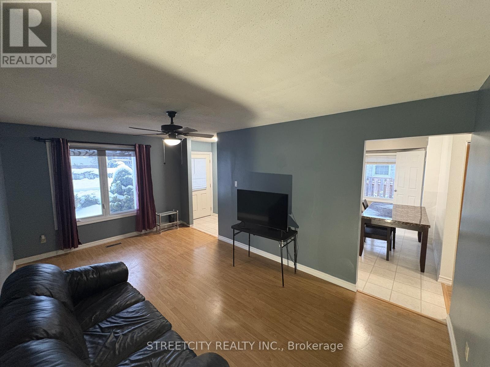 A living room with a black leather couch and a flat screen TV.