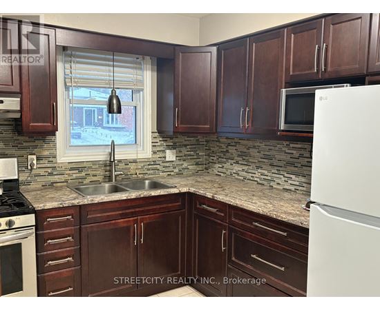 A kitchen with brown cabinets and a white fridge.