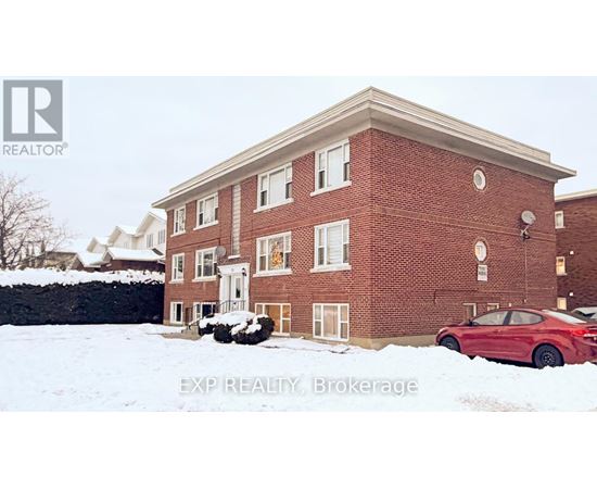 A red car is parked in front of a brick building.