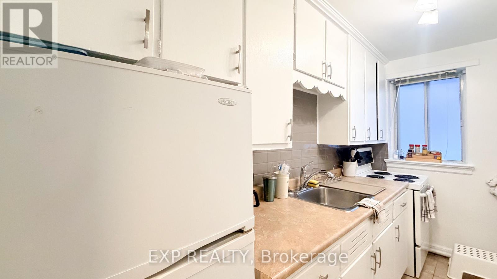 A kitchen with white cabinets and a white refrigerator.