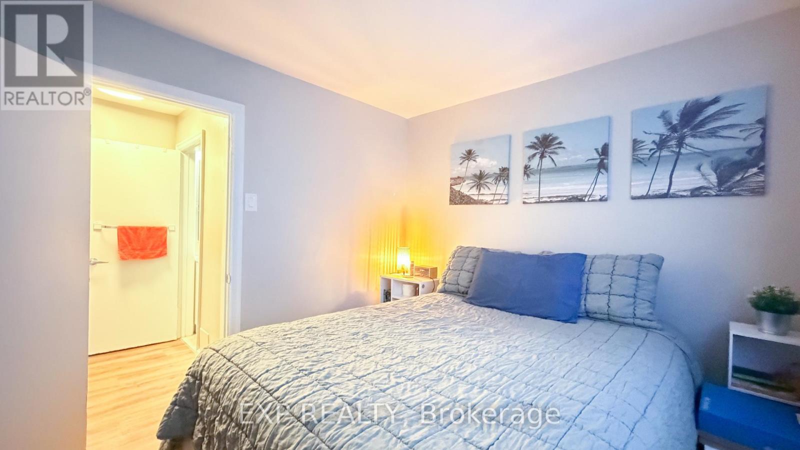 A bedroom with a bed, nightstand, and pictures on the wall.