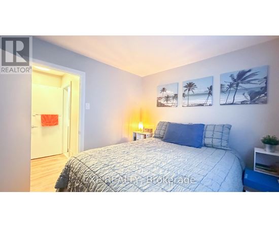 A bedroom with a bed, nightstand, and pictures on the wall.