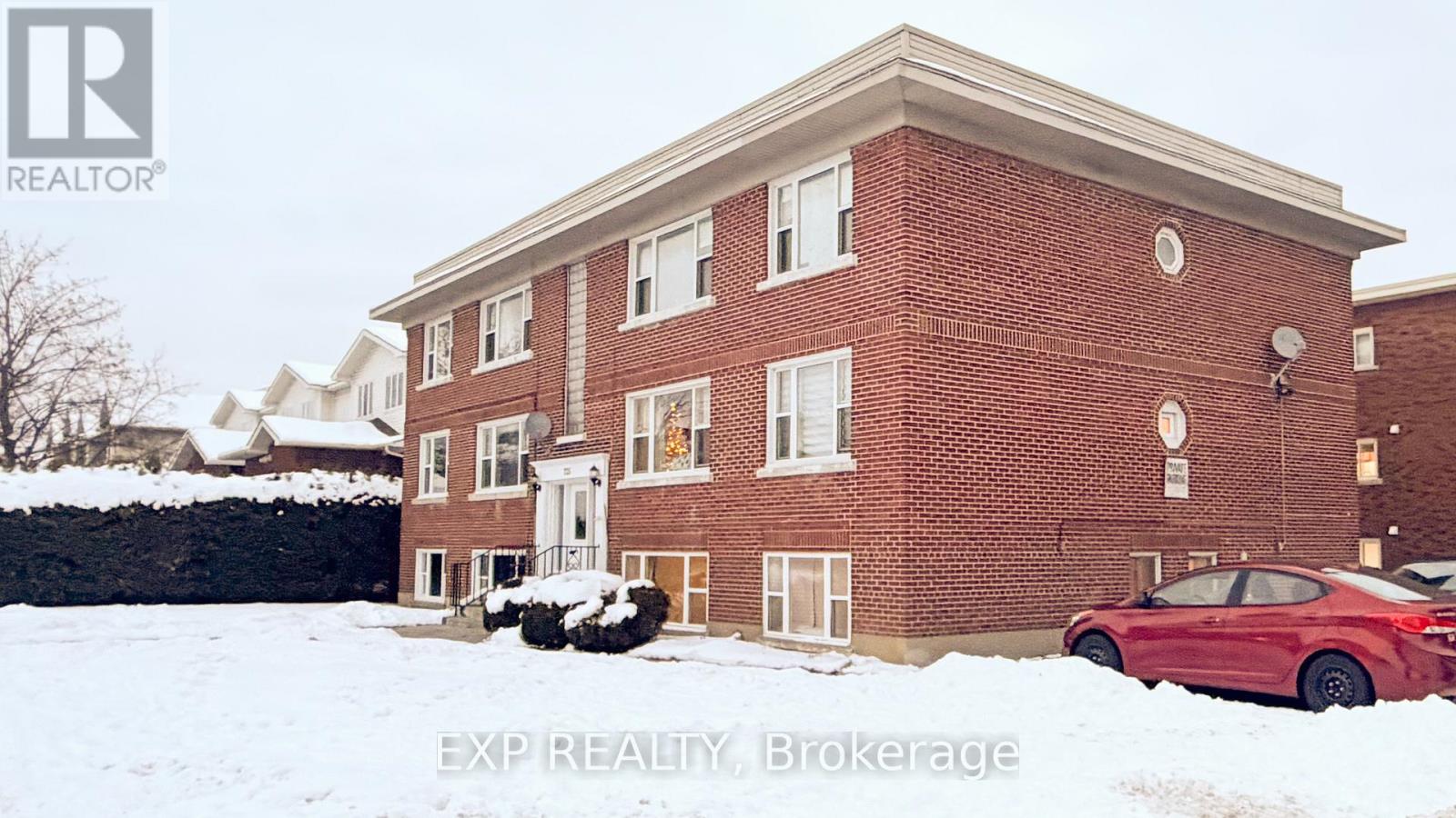 A red car is parked in front of a brick building.