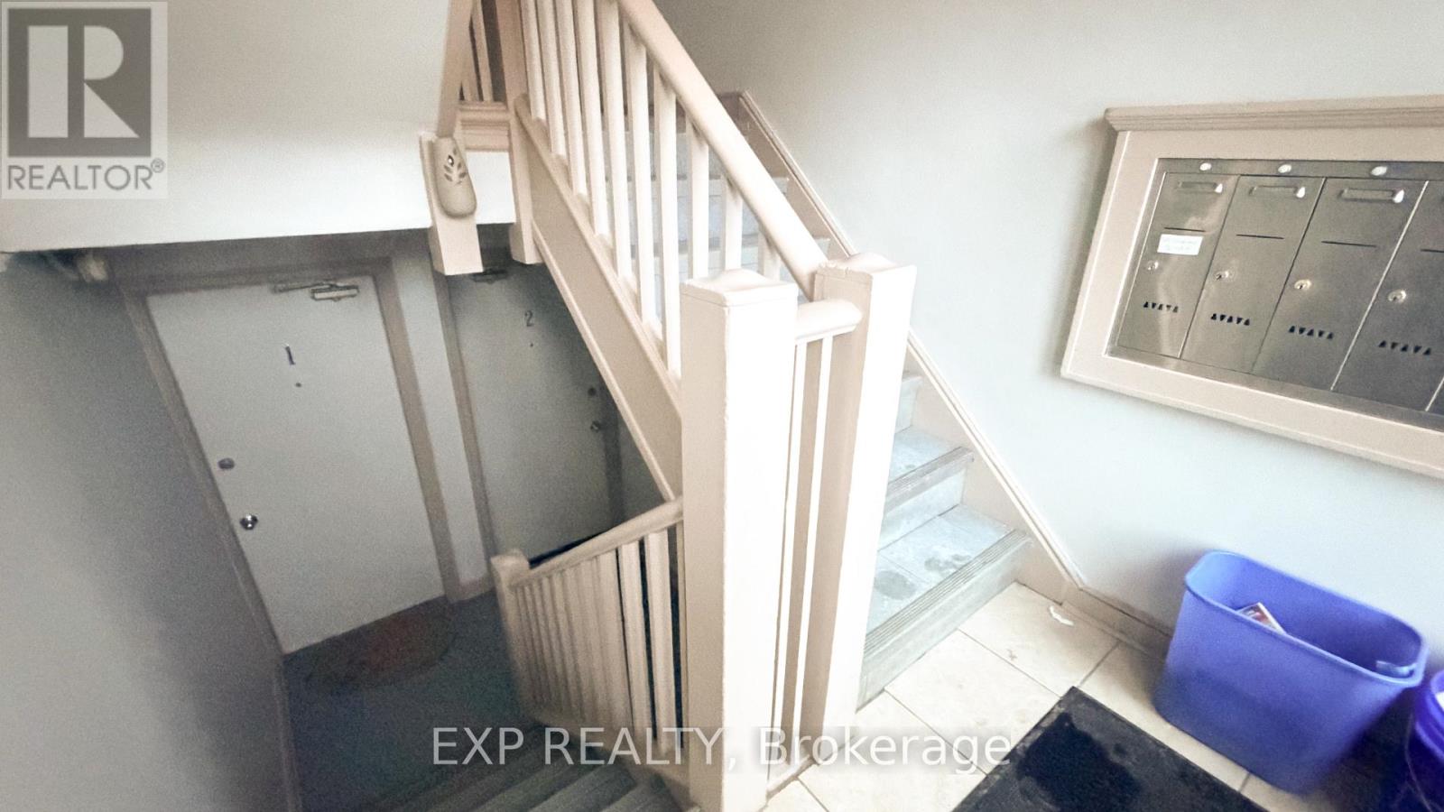 A staircase with a railing and a wall-mounted thermostat.