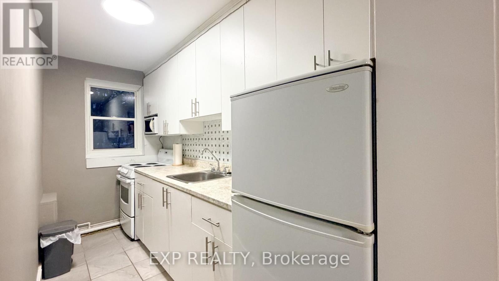 A kitchen with white appliances and cabinets.
