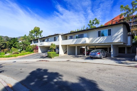 A car is parked in the driveway of a two-story building.