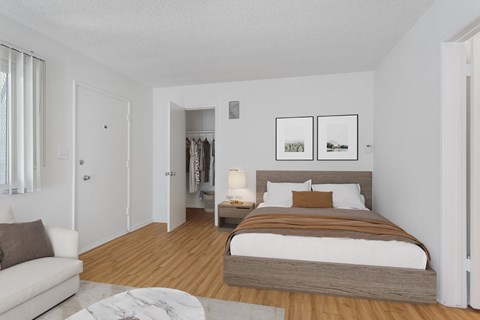 A bedroom with a bed, nightstand, and a couch.