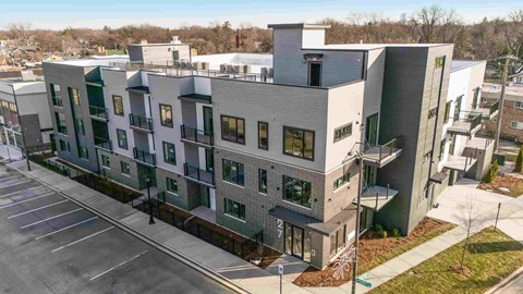 A modern apartment building with a parking lot in front.