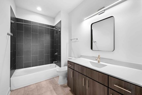A modern bathroom with a white sink and a black and white tiled shower.