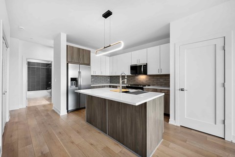 A modern kitchen with a white island and wooden floors.
