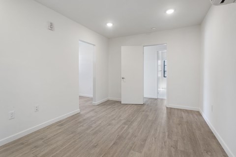 A room with white walls and wooden flooring with two doors.