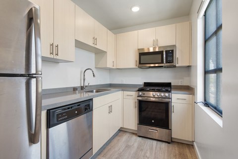 A modern kitchen with stainless steel appliances and wooden floors.