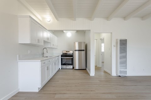 A kitchen with white cabinets and a wooden floor.