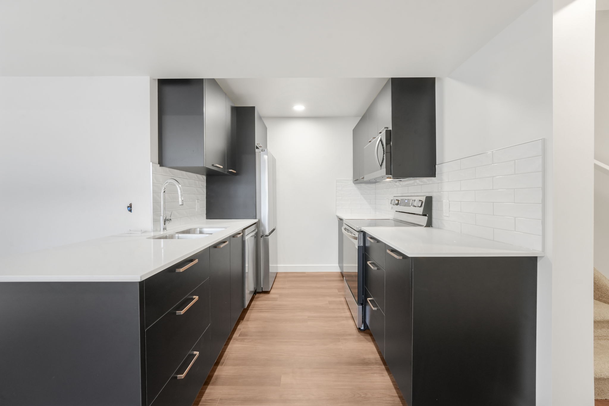 A modern kitchen with black cabinets and a white countertop.