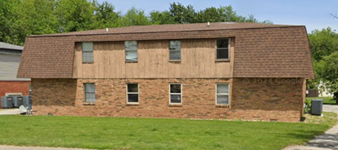 A brown building with a brown roof and four windows.