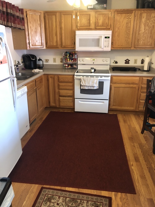 A kitchen with wooden cabinets and a white stove top oven.
