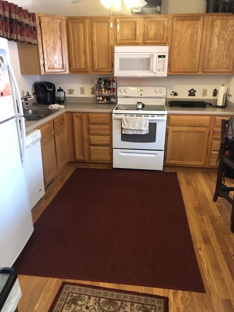 A kitchen with wooden cabinets and a white stove top oven.